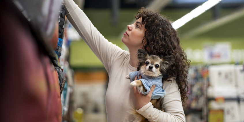 mulher segura cachorro de estimação dentro de supermercado