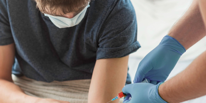 profissional de saúde realiza coleta de sangue em homem jovem