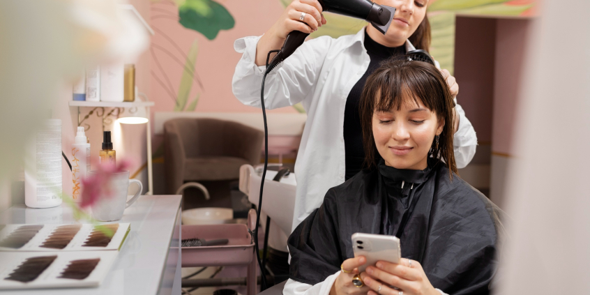 Mulher trabalha secando o cabelo de cliente
