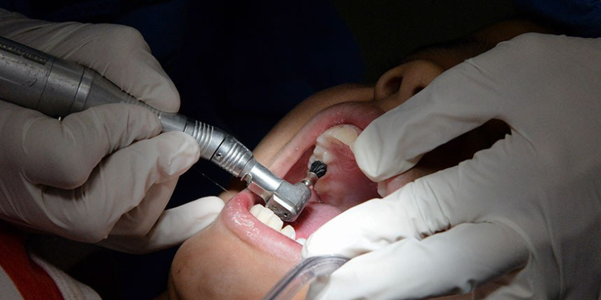 profissional dentista realiza atendimento em paciente que está com a boca aberta