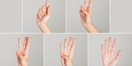 mãos exibem os sinais referentes à contagem de um a cinco em linguagem de sinais