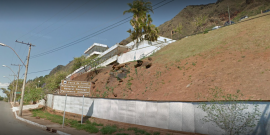 vista panorâmica da fachada do antigo hospital Hilton Rocha e parte da Serra do Curral. Placa sinaliza a área como patrimônio ambiental
