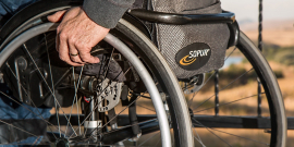 parte de trás de uma cadeira de rodas com uma mão sobre a roda