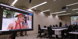 em primeiro plano,  tela de computador mostra indígenas no Plenário Helvécio Arantes