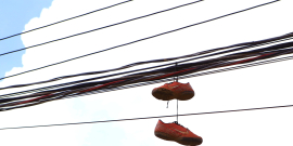 Imagem de fios de energia elétrica com um par de tênis pendurado