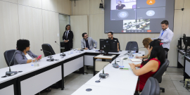 Vereadores no Plenário Helvécio Arantes, sentados com microfones na mesa à frente deles, e um telão atrás.