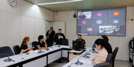 Vereadores discutem projetos no Plenário Helvécio Arantes. O telão atrás deles mostra videochamada com vereador presente virtualmente.