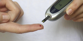 Mãos fazendo teste de glicemia, com furo no dedo indicador