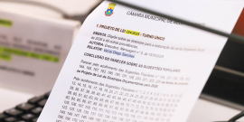 Mão segurando documento com pauta da reunião