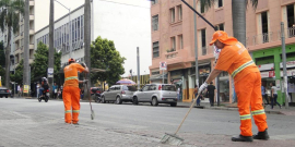 Dois garis varrendo uma rua