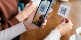 Pessoa usa o celular para ler QR Code em uma cafeteria