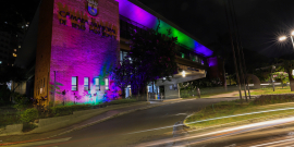 fachada da câmara municipal iluminada nas cores lilás, azul, verde e rosa