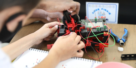 adolescente constróem e manuseiam pequeno robô
