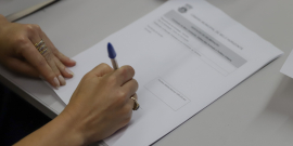 mãos de parlamentar assinando documento