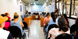 Moradores de costas para a câmera, voltados para mesa de audiência pública no plenário da CMBH