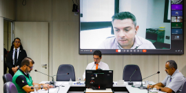 Vereador e convidados da audiência pública reunidos em torno da mesa na CMBH, com um participante online