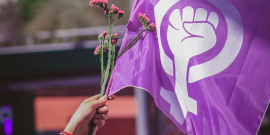 mãos hasteiam bandeira com símbolo do fim da violência contra a mulher