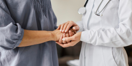 Imagem de médica e paciente segurando as mãos