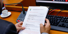 Mão de vereador segurando pauta da reunião de comissão