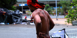 Morador em situação de rua com camisa vermelha na cabeça