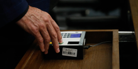mãos de parlametar operando terminal de votação