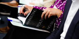 Pessoa lê livro Marketing Político no Brasil durante o Seminário