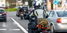 Motociclista trafega em rua de cidade