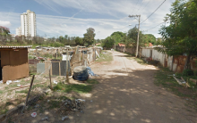 Rapazes caminham em rua de terra entre os barracos da Vila Felicidade, no Bairro Clafate