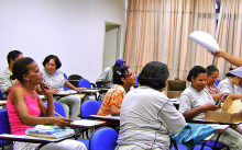 Mulheres adultas ocupam suas cadeiras em sala de aula