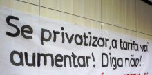 Faixa afixada na parede do plenário com a inscrição "Se privatizar, a tarifa vai aumentar! Diga não!"
