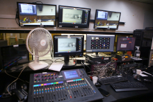 Sala de som. Cinco computadores exibem reunião em videoconferência