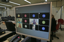 Monitor de computador exibe convidados em videoconferência. Ao fundo, cadeiras do Plenário Helvécio Arantes, vazias