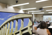 Foto mostra computador com imagem do Viaduto Santa Teresa e pessoas ao fubdo 