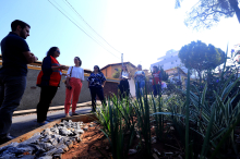 Seis mulheres e um homem, de pé, conferem jardim de chuva implementado no Bairro planalto, durante o dia.