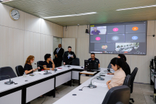Vereadores discutem projetos no Plenário Helvécio Arantes. O telão atrás deles mostra videochamada com vereador presente virtualmente.