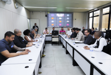 Imagem da reunião com participantes ocupando as cadeiras em torno da mesa em formato de U. O vereador Irlan Melo (Republicanos) está na cabeceira. 