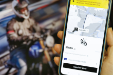 imagem de telefone celular aberto em aplicativo de transporte. em segundo plano, motociclista
