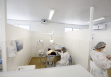 espaço interno de centro de saúde da capital, com profissional realizando atendimento odontológico em paciente