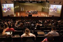 plateia assiste a evento em auditório, com pessoas presentes no palco