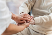 Mãos de pessoa jovem segurando mãos de idosa
