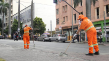 Dois garis varrendo uma rua