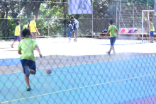 crianças com uniforme de escola brincam com bola em quadra esportiva