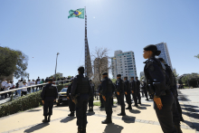 Guardas enfileirados em frente à bandeira do Brasil