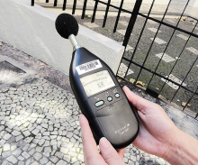 mãos segurando um aparelho medidor de nível sonoro