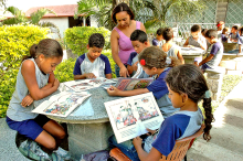 profissional de educação auxilia estudantes durante leitura de livro