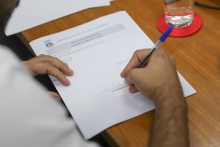 Mão de vereador assinando requerimento durante a comissão