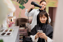 Mulher trabalha secando o cabelo de cliente